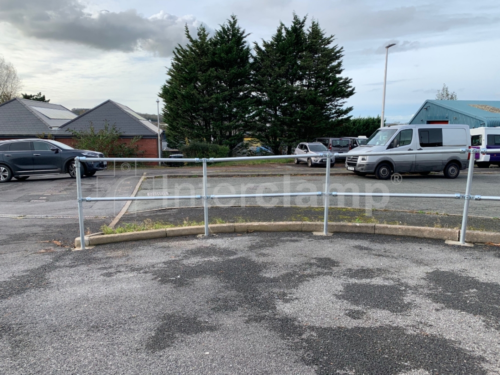 Heavy-duty guardrail at an industrial car park made with Interclamp key clamp fittings and tube, showcasing strong and reliable construction.